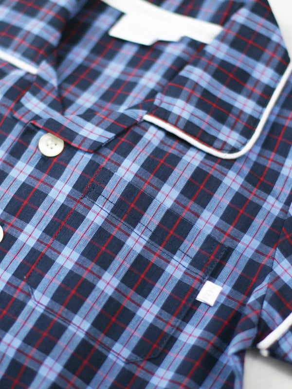 There’s no such thing as a basic check at Mini Vanilla! In our Short sleeve crisp summer cotton boys pyjamas we’ve blended navy with blue and red to create a  traditional look that’s perfect for lounging or sleeping. Made from super-soft 100% crisp cotton. The set is trimmed with white cotton piping. The top has an open collar and revere, single square pocket with MV tab and fastens with Mini Vanilla Engraved buttons. The crisp cotton comfy trousers have a fully soft elasticated waist and white piping at the hem to finish this very traditional boys pyjamas