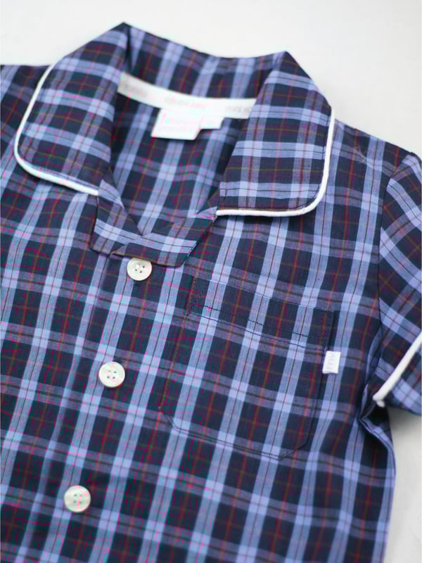 There’s no such thing as a basic check at Mini Vanilla! In our Short sleeve crisp summer cotton boys pyjamas we’ve blended navy with blue and red to create a  traditional look that’s perfect for lounging or sleeping. Made from super-soft 100% crisp cotton. The set is trimmed with white cotton piping. The top has an open collar and revere, single square pocket with MV tab and fastens with Mini Vanilla Engraved buttons. The crisp cotton comfy trousers have a fully soft elasticated waist and white piping at the hem to finish this very traditional boys pyjamas
