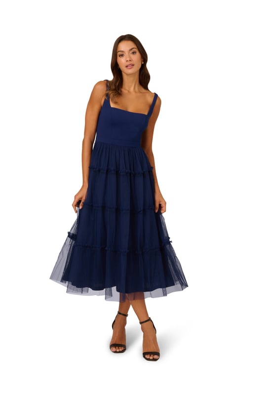 Modern fabric mixes make this classic fit and flare dress a sweet look. This midi dress features a fitted bodice with tank straps, a square neckline, and a tiered skirt. Fully lined, the bodice is crafted from a knit fabrication while the skirt is overlaid in mesh for added sweep. Pockets and a square back with centre zip closure complete this delightful party dress. Styled with nude heels and sparkling accessories, this midi dress is a timeless look from wedding guest duty to cocktail parties