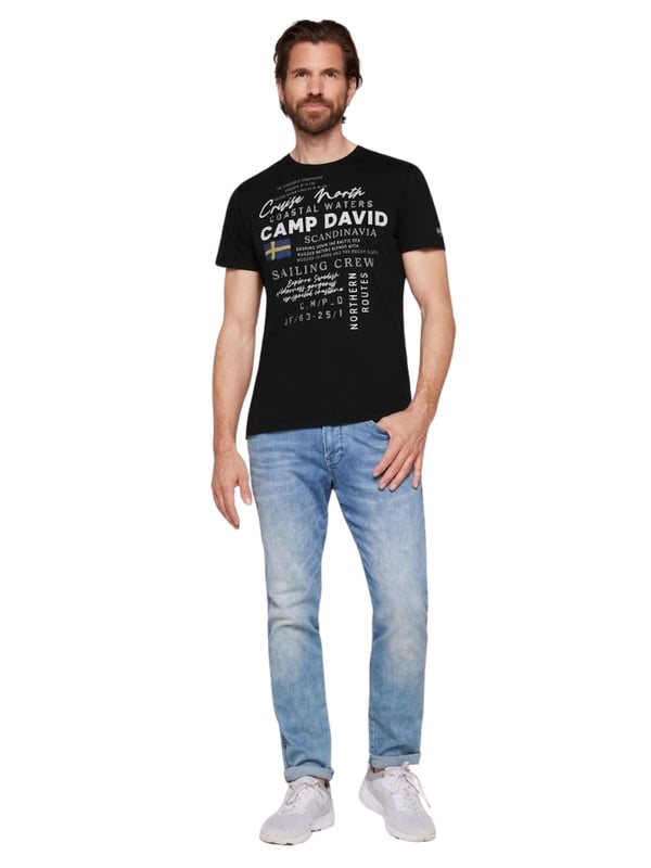 Dieses Herren-T-Shirt kombiniert modernes Design mit sportlichen Akzenten. Die normale Passform und der Rundhalsausschnitt mit Rippblende sorgen für einen klassischen Look, während ein gestreiftes Necktape im Inneren einen Hauch von Raffinesse hinzufügt. Kontrastnähte an den Schultern setzen dynamische Akzente und betonen die maskuline Silhouette. Der Front-Print mit Rubber-Details verleiht dem Shirt einen coolen, strukturierten Look. Ein kleiner Logo-Print auf der Rückseite und ein Label-Patch am linken Ärmel runden das Design ab. Das weiche Material bietet höchsten Tragekomfort, ideal für jeden Tag. Ein perfektes Shirt für den stilbewussten Mann, der Wert auf Details legt. Ob lässig oder sportlich, dieses T-Shirt ist ein echter Hingucker.