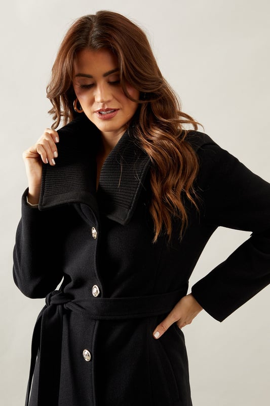 Elegant knitted collar for added sophistication
        Wrap design with button-through closure for versatile styling
        Long length offers maximum coverage and warmth
        Belted waist creates a flattering silhouette
        Functional side pockets for practicality
    
    This Wallis Knitted Collar Button Through Wrap Coat is the epitome of refined elegance. Perfect for the woman who appreciates sophistication without compromising on comfort, this coat is a versatile addition to any wardrobe. The wrap design allows for customisable fit, while the button-through closure adds a touch of classic charm. Style it over a sleek midi dress and pair with heeled boots for a polished look at formal events. For smart casual occasions, layer it over tailored trousers and a fine knit jumper, completing the ensemble with leather ankle boots. The long length and belted waist not only provide warmth but also create a striking silhouette that's sure to turn heads. Whether you're attending a business meeting or heading to a sophisticated dinner, this coat will ensure you look impeccably put-together while feeling effortlessly comfortable.