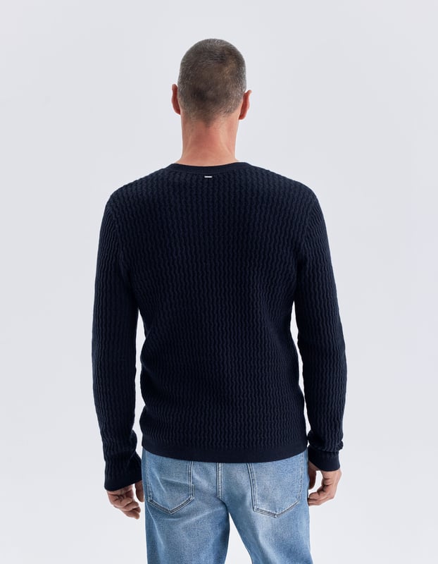 This navy jumper has round neck and long sleeves. It is relieved knit with fine twists.