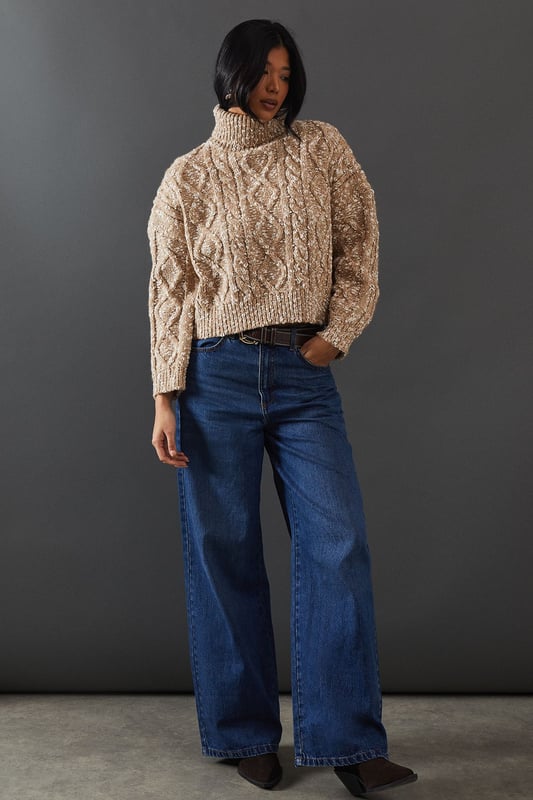 Intricate cable knit pattern for a textured look
        Cosy roll neck design for extra warmth
        Relaxed, oversized fit for comfort and style
        Dropped shoulders for a contemporary silhouette
        Ribbed cuffs and hem for a snug finish
    
    This Cable Knit Roll Neck Jumper from Warehouse is the epitome of casual chic. The intricate cable knit pattern adds depth and interest to your outfit, while the oversized fit creates a relaxed, effortless vibe. Perfect for those chilly autumn days or cosy winter evenings, this jumper is versatile enough to dress up or down. For a laid-back look, pair it with wide-leg jeans and trainers, as shown in the image. To dress it up a bit, try tucking the front into a leather midi skirt and adding ankle boots. The neutral tone makes it easy to style with various colours and textures in your wardrobe. Whether you're heading to a casual family gathering or meeting friends for a coffee, this jumper will keep you warm and stylish. Its timeless design ensures it will remain a staple in your wardrobe for seasons to come.