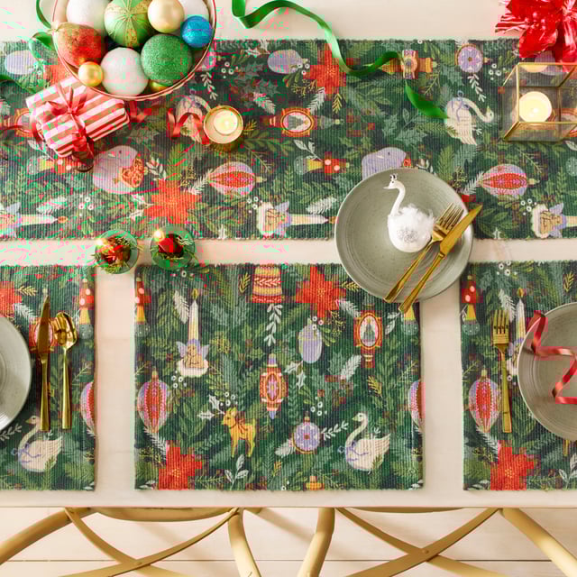 Get into the Christmas spirit with this wonderfully festive table runner. Featuring a digital printed design on woven polyester fabric of Christmas foliage and traditional tree decorations, including vintage baubles, candles and even a swan in vivid seasonal colours. This beautiful table runner will transform and add some instant seasonal cheer to your Christmas dining table.