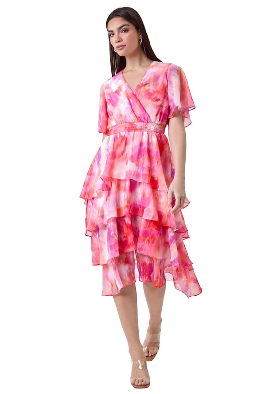 Abstract Print Chiffon Tiered Midi Dress from Roman. Discover pure elegance with this abstract print tiered midi dress from the Ariella collection. This wedding guest staple features a soft chiffon fabric with a flattering tiered silhouette and a v-neckline. Designed with a wrap front and shirred stretch waist for a fit and flare shape, this will be flattering for any formal event. The vibrant abstract print, split detail skirt, and short floaty sleeves add a touch of femininity to the finished look. Whether you're ready for a day at the races or you're Mother of the Bride, this dress is easy to pull on overhead and style with heels for timeless occasionwear.