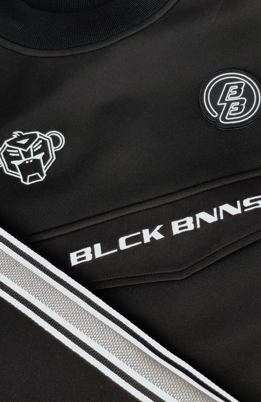 100 % poliéster Cuello alto Parche de marca Convoy bordado en el pecho Solapa con la firma BNNS en negro en la parte delantera Cinta de rayas deportivas en las mangas Se puede combinar con PANTALONES DEPORTIVOS MIAMI TAPED