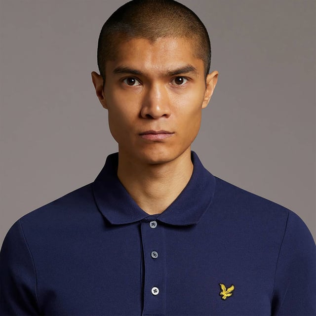 The ultimate Lyle & Scott style icon, our Plain Polo Shirt has a been at the forefront of fashion for decades. Available in an array of colours and constructed from a lightweight, soft cotton-blend, our polos are a wardrobe essential. Imbued with elastane so added stretch and finished with classic ribbed collar and cuffs, three-button placket with detail stitching, plus our signature Golden Eagle, a mark of true British heritage. 
 
Fit: Regular
It is crafted to fit the body neither too tightly or too loosely, leaving you with a classic, timelessly stylish look. We recommend you order your usual size, but if you're caught between two, go a size up.
