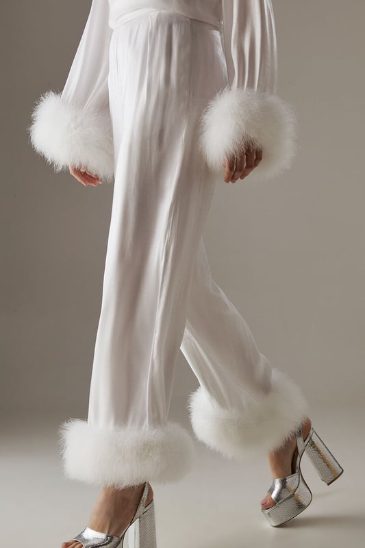 Luxurious feather trim adorning cuffs and hem
        Wide-leg silhouette for a dramatic, flowing effect
        High-waisted design for a flattering fit
        Iridescent fabric adding a subtle shimmer
        Ankle-length cut perfect for showcasing statement footwear
    
    Make a grand entrance at your next formal event with these show-stopping wide-leg trousers from Warehouse. The iridescent fabric catches the light beautifully, whilst the opulent feather trim at the cuffs and hem adds a touch of old Hollywood glamour. Style these trousers with a sleek, fitted top to balance the voluminous silhouette. For an ultra-chic ensemble, pair with metallic platform sandals and a clutch bag. These trousers are versatile enough for a range of occasions, from black-tie galas to winter weddings. The high-waisted cut elongates the legs, creating a statuesque silhouette that's sure to turn heads. Embrace your inner fashionista and let these trousers be the star of your outfit.