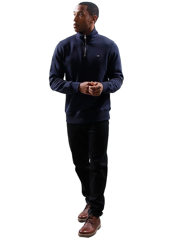 This versatile half-zip sweatshirt combines comfort and style with a premium cotton-polyester blend that's perfect for transitional weather. Featuring a small, intricately embroidered GANT graphic on the chest, it showcases a subtle yet elevated design. The ribbed hem and cuffs create a tailored silhouette. Designed for a regular fit, the half-zip collar adds a touch of sporty elegance, while the durable fabric ensures long-lasting wear.