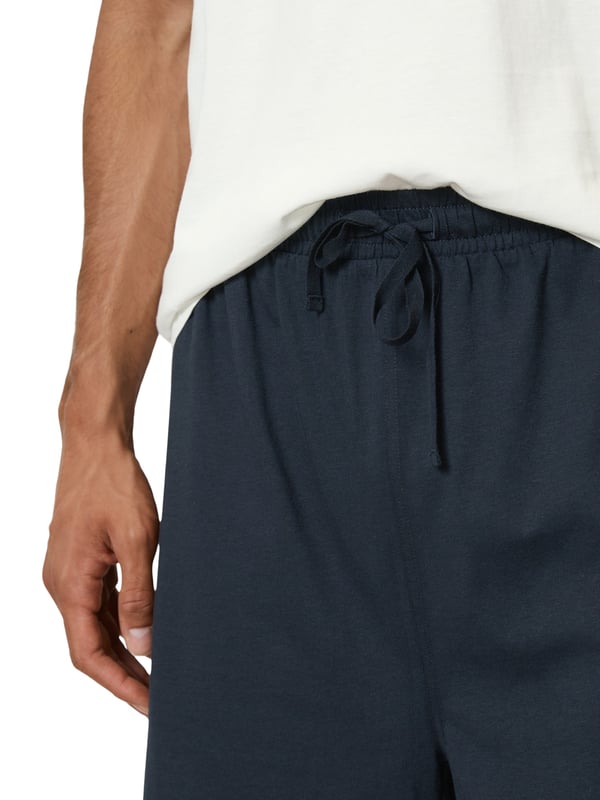 Deze tweedelige pyjama voor heren biedt perfect comfort voor ontspannen nachten. De top heeft een ronde halslijn en verlaagde schouders voor een losse en comfortabele pasvorm. De rechte zoom en logoprint op de voorkant geven de pyjama een moderne look. De shorts hebben een elastische tailleband en een trekkoord in de tailleband voor een optimale pasvorm. Deze pyjama is gemaakt van zacht, ademend materiaal en is zeer comfortabel om te dragen. Deze pyjama is ideaal voor warme zomeravonden of gezellige uurtjes thuis en is de perfecte keuze voor stijlbewuste mannen.