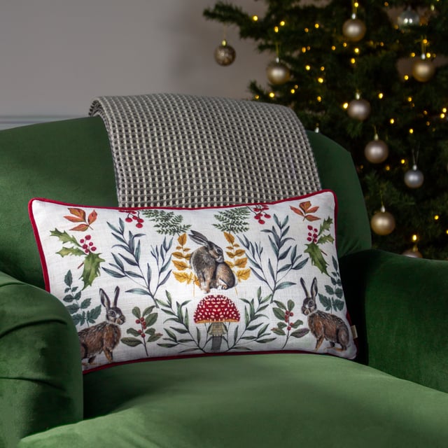 An adorable cushion featuring three posing winter hares among winter foliage and a toadstool, set on a fresh white background. The hand painted watercolour design is printed on polylinen fabric, with a plush plain red velvet reverse, contrasting piped trim and zip fastening. Ideal for bringing a touch of nature to your home.