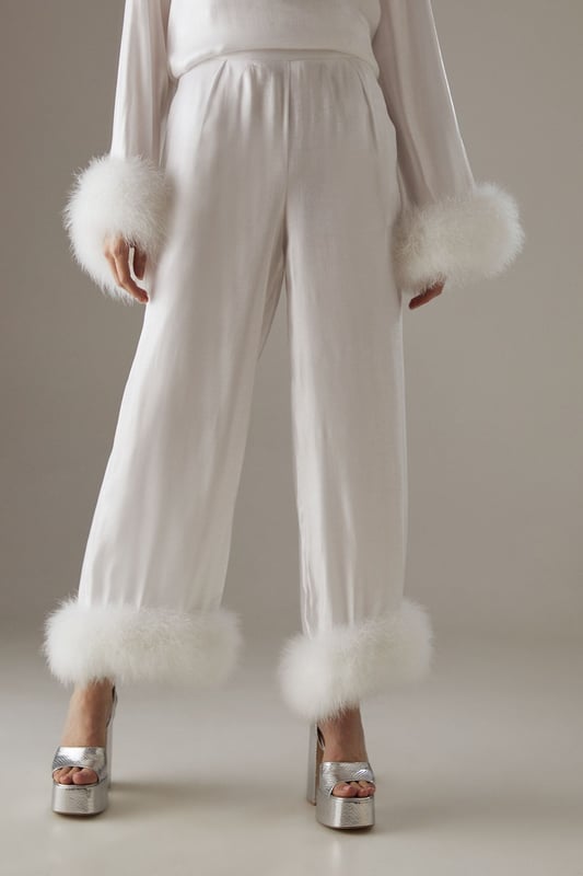 Luxurious feather trim adorning cuffs and hem
        Wide-leg silhouette for a dramatic, flowing effect
        High-waisted design for a flattering fit
        Iridescent fabric adding a subtle shimmer
        Ankle-length cut perfect for showcasing statement footwear
    
    Make a grand entrance at your next formal event with these show-stopping wide-leg trousers from Warehouse. The iridescent fabric catches the light beautifully, whilst the opulent feather trim at the cuffs and hem adds a touch of old Hollywood glamour. Style these trousers with a sleek, fitted top to balance the voluminous silhouette. For an ultra-chic ensemble, pair with metallic platform sandals and a clutch bag. These trousers are versatile enough for a range of occasions, from black-tie galas to winter weddings. The high-waisted cut elongates the legs, creating a statuesque silhouette that's sure to turn heads. Embrace your inner fashionista and let these trousers be the star of your outfit.