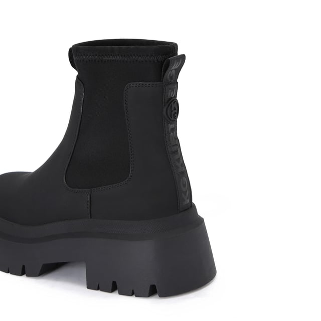 The Thea2 is a black boot with chunky style, there is a stretch ankle for slip-on ease. The sole is extra chunky with large tread. The back of the ankle features a brown monocle and KG Kurt Geiger branded tape.