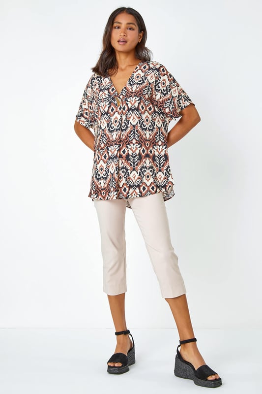 Button Detail Aztec Print Top from Roman. Step into the Summer with neutral prints and relaxed silhouettes. This overshirt has a bold statement button at the front, a feminine v-neckline and short batwing sleeves. It’s designed from a loose woven material for a comfortable and breezy everyday fit. Pair this ikat printed tee with a pair of cropped trousers and wedges for a stylish casual Spring Summer look.