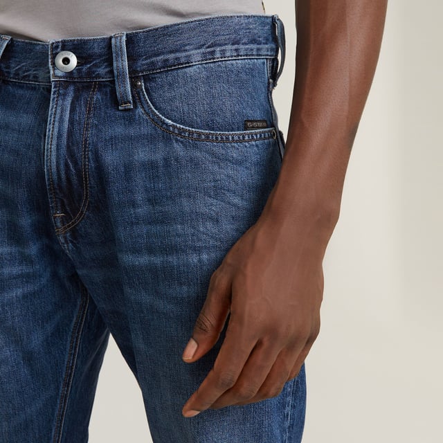 Zip fly. 5 pockets, incl. coin pocket caught in the seam. Tool loop at the side. G-Star RAW label at the back, made from a leather-like paper fabric. Zip & button closure. Mid waist. The Lenney jeans is designed in a straight fit that widens in a bootcut silhouette. The tool loop at the side adds interest. 100% Cotton. Rigid. Weight 11.3 oz. Bootcut