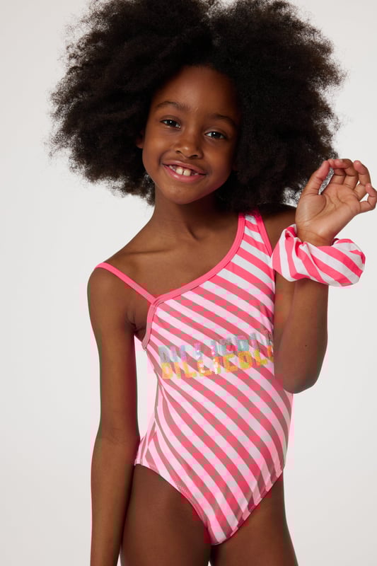 Introducing the elegant Girls Swimsuit with 2 Scruchies in Pink by Billieblush - the ideal holiday ensemble for your little fashionista.  Fashion-forward Design: Boasting a stylish, vibrant pink colour sure to turn heads at the pool or beach. High-Quality Fabric: Crafted with premium material, ensuring softness and comfort for your child's delicate skin. Unique Extras: Comes with matching scrunchies, perfect for creating cute and coordinated hairstyles. Renowned Brand: Brought to you by Billieblush, a symbol of premium children's fashion.This splendid swimsuit is a wardrobe must-have to make your little one shine in style this holiday season. Order now.