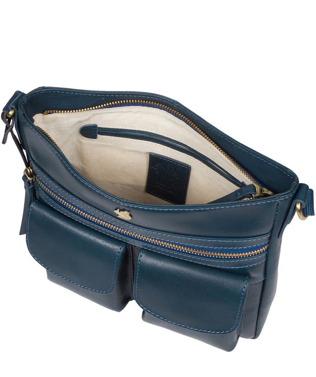 The 'Baby Bon' cross body bag from Conkca London is handcrafted from full grain genuine leather for a beautiful finish. A smaller version of the original 'Bon' cross body bag. A zip-over top conceals the central compartment that is lined with natural and untreated 100% cotton. The zipped pocket and two pockets secured with magnetic fastenings on the front of the bag, provide plentiful on-the-go storage. Comes with an adjustable fabric strap with a maximum drop length of 70cm. Adorned with the inimitable Conkca squirrel charm and embossed logo.