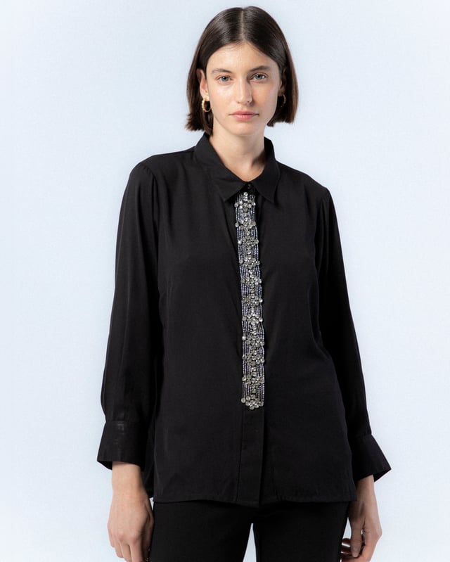 Atrévete con la camisa negra de pedrería Lucía. Con el detalle de las pedrería en el centro de la prenda, la camisa Lucía se convierte en tu mayor aliada para looks de noche este invierno.
 
 
 
 Camisa con cuello solapa.
 
 Detalle de pedrería plata en tapete.
 
 Manga larga acabada con puño.
 
 Forro de satén por separado.