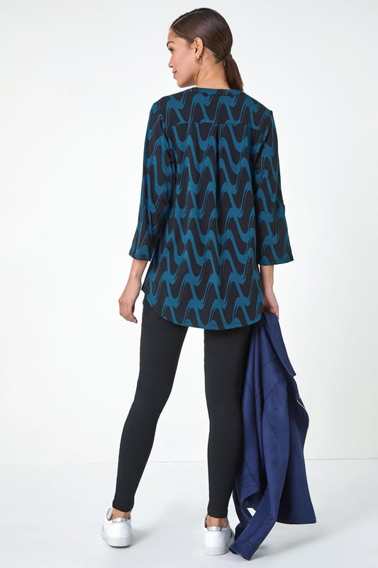 Geometric Print Stretch Blouse from Roman. Elevate your wardrobe this season with our stunning abstract blouse. The bold print and woven silhouette make it versatile for any occasion. The notch neckline, adjustable 3/4 length sleeves and front button details adds a touch of sophistication. Pair it with black jeans and boots for a daytime look or add tailored trousers perfect for those desk-to-dinner days