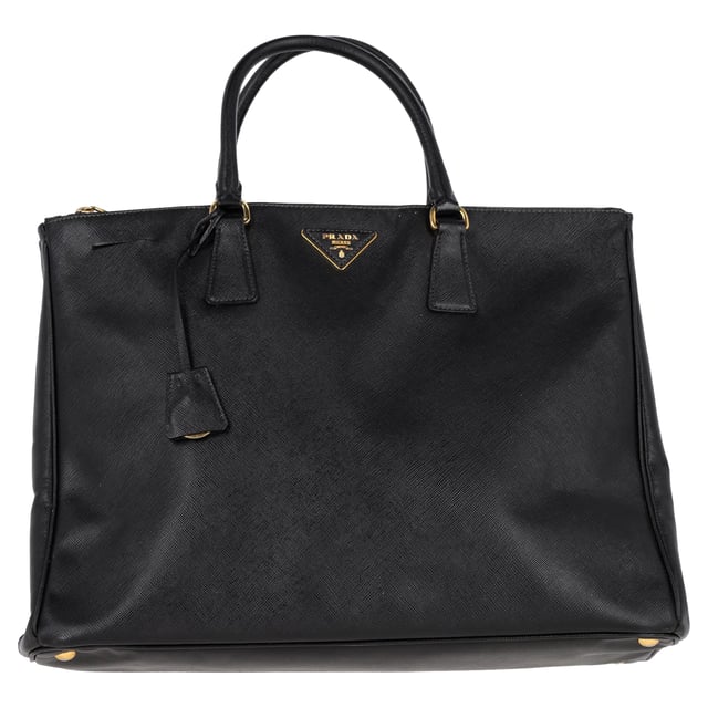 VINTAGE, NEUPREIS WIE NEU  
Die Prada Double Zip Executive Tote Bag aus schwarzem Saffiano Lux Leder ist ein elegantes und vielseitiges Accessoire. Hergestellt aus strapazierfähigem und luxuriösem Saffiano-Leder, vereint diese Tote praktische und stilvolle Eigenschaften und bietet ausreichend Platz für alle Ihre täglichen Essentials und mehr. Mit ihrem schlanken Design und funktionalen Merkmalen, einschließlich zweier Außentaschen mit Reißverschluss und einem großen Hauptfach, ermöglicht diese Tasche eine bequeme Organisation Ihrer Sachen. Abgerundet mit einer schicken Clochette und einem Schlüsselring-Detail ist diese Tasche der perfekte Begleiter für den Alltag und kombiniert mühelos Eleganz und Funktionalität.

Prada Double Zip Executive Tote Bag aus schwarzem Saffiano Lux Leder  
Zustand: Ausgezeichnet  
Abnutzungserscheinungen: Kein Einzelhandelsetikett, keine sichtbaren Gebrauchsspuren,  
Verpackung: Keine  
Farbe: schwarz  
Material: Leder | Saffiano-Leder  
Größe: Einheitsgröße  
Maße: Breite: 180; Höhe: 300; Länge: 420; Henkelabfall: 130; Gurtlänge: 300  
SKU: NAPPUGBBA399031W