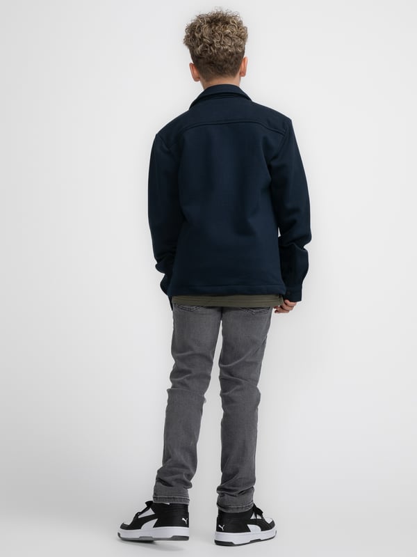Overshirt aus Sweatstoff mit langen Ärmeln. Dieses Hemd verfügt über einen klassischen Kragen, einen Druckknopfverschluss, zwei Brusttaschen mit Druckknopfverschluss und ein Emblem auf einer Brusttasche. Das Overshirt ist mit Druckknöpfen an den Ärmeln versehen. Haben Sie Schwierigkeiten, sich zwischen zwei Größen zu entscheiden? Dann wählen Sie die größere Größe. Sweatstoff, klassischer Kragen, Druckknopfverschluss, zwei Brusttaschen, 100 % Baumwolle.