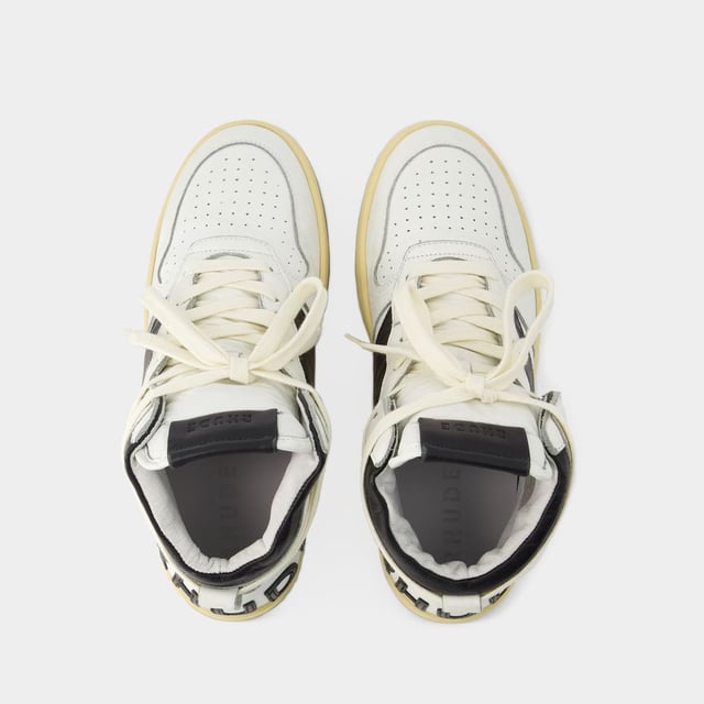 Presentamos las zapatillas Rhecess de Rhude, donde la frescura urbana se une a la comodidad contemporánea. Estas zapatillas fusionan a la perfección un diseño moderno con un guiño al estilo streetwear, mostrando una silueta única perfecta para ir a la moda statement. Para elevar tu look con estas zapatillas statement, considéralas la base de un conjunto moderno de inspiración callejera. Combínalas con unos vaqueros desgastados, una sudadera con capucha de estampado gráfico y unas gafas de sol atrevidas para conseguir un look vanguardista sin esfuerzo, perfecto para un día con amigos o una noche informal en la ciudad. Rhude Las zapatillas Rhecess de brand ejemplifican el compromiso de la marca con la calidad y la moda, ofreciéndote una opción de calzado distintiva y versátil que combina sin esfuerzo el encanto moderno con el estilo urbano. Sal con confianza, mostrando tu sensibilidad única por la moda y tu estilo de entrenador contemporáneo. Colores: Blanco - Blanco/Negro. Material principal: piel de ternero lisa. Material de la suela: caucho. Material del forro: algodón. Cierre: cordones en la parte superior. Forma de la punta: almendra. Ajuste: fiel a la talla - Talla: