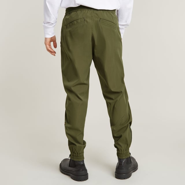 Zip fly, drawcord added. Inset pockets, single back pocket. Stretchable cuffs, relaxed width. Zipper at the lower leg. Pleats inner knee. Zip & button closure. Mid waist. Woven trainer RCT is designed in a loose fit with a relaxed cuff. Inset pockets are combined with a single pocket at the back. The zippers at the ankle add detail. 65% Polyester (Recycled), 35% Elastomultiester. Comfortable stretch. Tapered