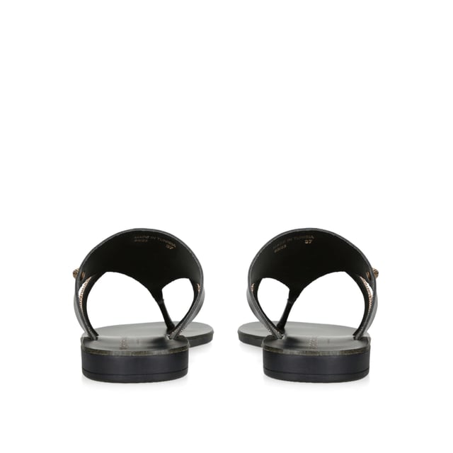 The KGL Strand is a black leather toe post sandal. There is a smaller, crystal embellished strap across the foot. The antiqued brass Eagle head sits on the outer side.