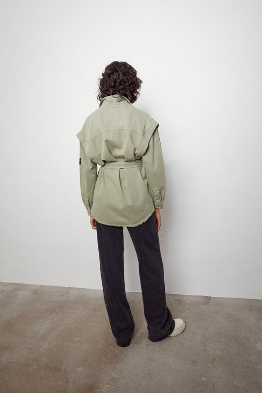 This khaki shirt with removable belt has military badges on the chest and sleeve and two patch pockets on the chest. It has a shirt collar, long sleeves, details at the shoulders and a ripped effect on the bottom. Button fastening.