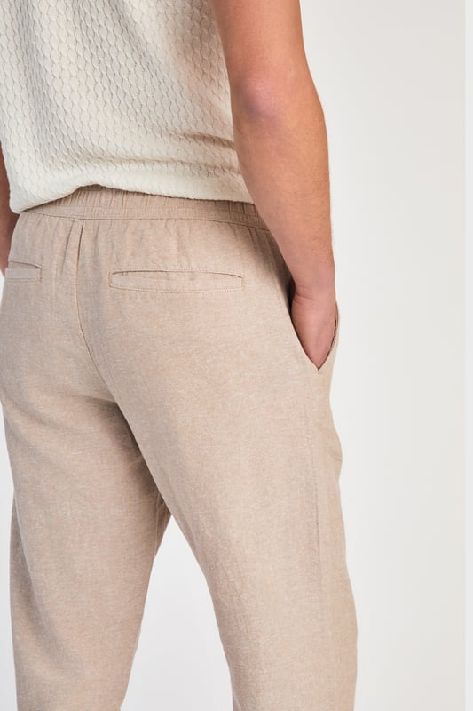 Beige Linen Blend Classic Fit Trousers Get stylish with these linen trousers from Nines by Kensington Eastside. Designed in a classic fit, these trousers feature an elasticated waistband and two side pockets. Made from a breathable blend of linen and cotton, these trousers are perfect for both casual and formal occasions. Machine washable for easy care, they are a versatile addition to any wardrobe.