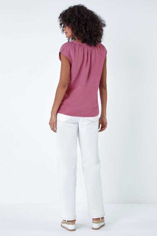 V-Neck Pleat Detail Cotton Top from Roman. Elevate your Summer basics with this breezy v-neck tee! Crafted from cooling cotton, this sleeveless top features a chic v-neckline completed with pleating for a touch of subtle sophistication. Perfect for casual outings, this t-shirt pairs effortlessly with wide-leg trousers and sandals for timeless Summer style.