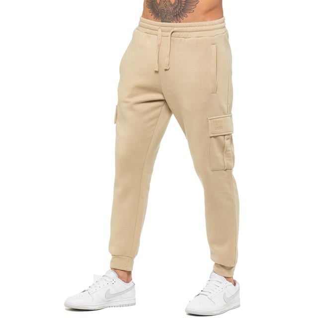 Enzo Mens Regular Fit Cargo Joggers. Features 2 Side Slash Pockets, 2 Cargo Pockets, Single Welt Back Pocket. Brushed Back Inner Fleece. Elasticated Waistband With Adjustable Drawstring. Cuffed Ankle. Features EZ Logo.