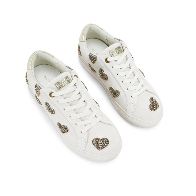 The Kurt Geiger Lane Love sneaker is crafted from a white leather with crystal embellished fabric hearts across the upper. There are two gold leather patches on the tongue and heel with gold foil branding.