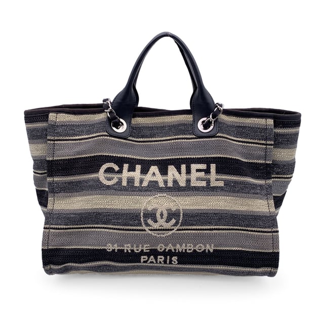 VINTAGE, RRP AS NEW
Beautiful Chanel 'Deauville' tote, crafted in black, grey and beige striped canvas with a white 'Chanel CC31, Rue cambon - Paris' logo. Period/Era: 2018/2019. Double black eather top handles and silver metal and interwoven leather shoulder straps. Magnetic button closure on top. The interior is in beige canvas lining. 2 side zip pockets inside. Leather strap with hook inside. 'CHANEL - made in Italy' tag inside. ity hologram tag inside Condition Rating: B - VERY GOOD CONDITIONCondition Details: Gently used. Some normal wear of use on bottom corners. Some darkness, small stains and normal wear of use on the internal lining. The fabric of the upper border is slightly discolored. Please, check carefully the photos or ask if you have any doubts. Measurements (cm):Depth: 20.3Height: 25.4Length: 43.2Other Details: Dustbag? NoKeys? NoBox? NoMeasurments:  width: 203 mm length: 432 mm height: 254 mm