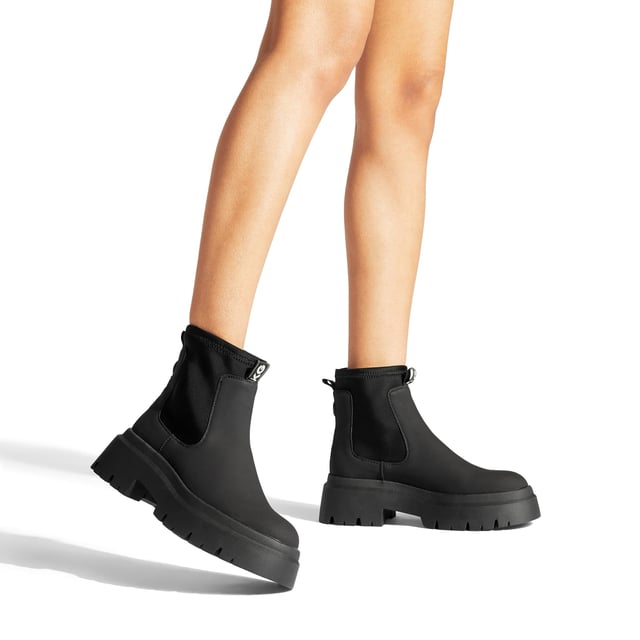 The Thea2 is a black boot with chunky style, there is a stretch ankle for slip-on ease. The sole is extra chunky with large tread. The back of the ankle features a brown monocle and KG Kurt Geiger branded tape.