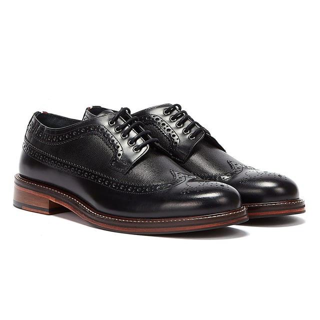 Ben Sherman Archie Brogue Herren Schwarz Schuhe Ein raffinierter Schuhstil, der perfekt ist, wenn Turnschuhe einfach nicht ausreichen. Diese Brogues von Ben Sherman verfügen über ein hochwertiges Obermaterial aus Leder mit dekorativen Perforationen und einer traditionellen Brogue-Konstruktion mit Flügelspitze. Gesichert mit einem 5-Augen-Schnürverschluss und mit einer klassischen gestapelten Sohle mit Gummieinsatz abgeschlossen.