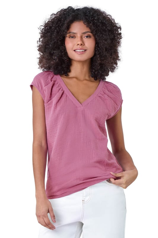 V-Neck Pleat Detail Cotton Top from Roman. Elevate your Summer basics with this breezy v-neck tee! Crafted from cooling cotton, this sleeveless top features a chic v-neckline completed with pleating for a touch of subtle sophistication. Perfect for casual outings, this t-shirt pairs effortlessly with wide-leg trousers and sandals for timeless Summer style.