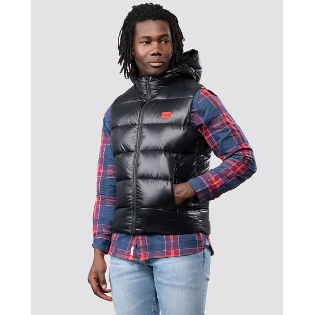 This sporty Water Repellent Puffer Hooded Gilet from HUGO is the perfect piece to elevate your wardrobe this season with sustainable style. Crafted from water-repellent recycled nylon and padded with sustainably sourced recycled fibres providing warmth and comfort. Featuring an insulated hood with full zip closure, elasticated binding and front zip pockets. Finished with a signature HUGO logo patch on the chest.Slim Fit, Water-Repellent Recycled Nylon Shell, Recycled Polyester Padding, Insulated Hood, Full Zip Closure, Twin Zip Front Pockets, Internal Zip Pocket, HUGO Branding. -Style & Fit:Slim Fit, Fits True to Size. Composition & Care:Shell: 100% Recycled Polyamide, Fill: 100% Recycled Polyester, Machine Wash.
