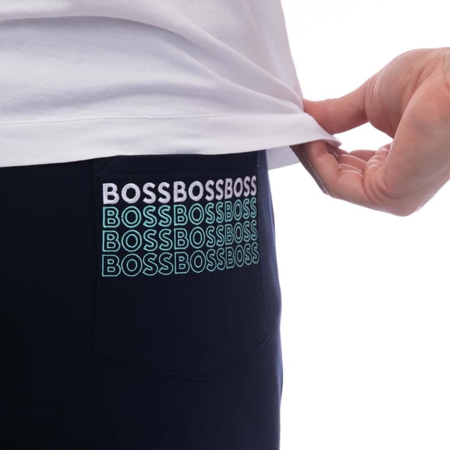 Mens BOSS Hadiko 1 Tracksuit Bottoms in dark blue.- Elasticated waist with drawcord.- Front slant pockets.- Rear patch pocket with repeat embroidered logo stripes.- Ribbed cuffs.- Embroidered BOSS logo at left thigh.- 47% Cotton  46% Polyester  7% Elastane.  Machine washable.- Ref: 50497194402