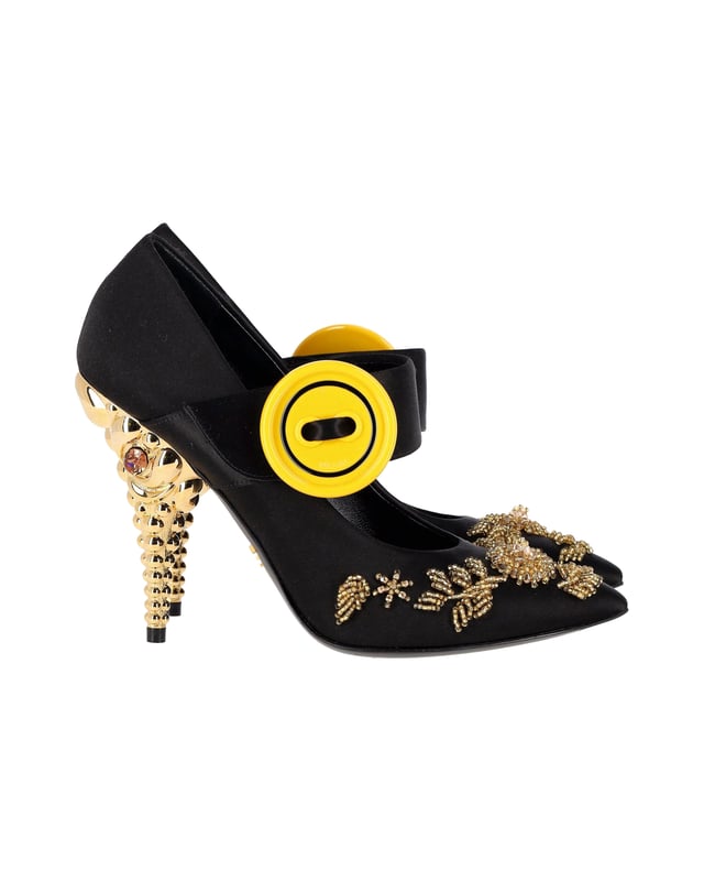 VINTAGE, UVP WIE NEU  
Diese atemberaubenden Pumps spiegeln Pradas exquisite Handwerkskunst im Schuhbereich wider. Hergestellt aus glattem Satin in einem schwarzen Farbton, verfügen sie über filigrane Verzierungen auf dem Obermaterial, einen Riemen im V-förmigen Design, der mit übergroßen gelben Knöpfen befestigt ist, und schlanke, spitze Zehen. Charakteristisch für die Pumps sind die atemberaubenden mit Kristallen besetzten Absätze in Gold-Optik.  

Prada Verzierte Gold- und Kristallabsatzpumps aus schwarzem Satin  
Zustand: sehr gut  
Material: Satin  
Größe: EU37  
Tragespuren: leichte Abnutzung an der Sohle  
SKU: 360962