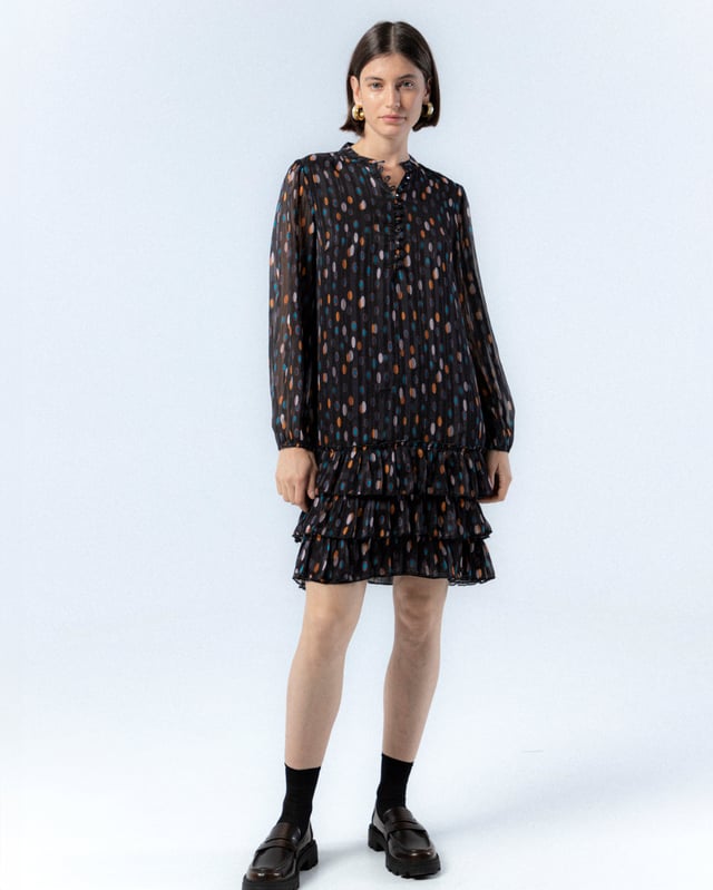 El vestido de lunares Alejandra, con su encantador estampado de lunares en tonos cálidos sobre fondo oscuro, te hará sentir la magia del otoño. Su diseño elegante y favorecedor es ideal para cualquier evento, añadiendo un toque de sofisticación y alegría a tu look.
 
 
 
 Vestido corto. 
 
 Abertura en escote con cierre de botones hasta la cintura. 
 
 Botones con aplique de piedras a mano. 
 
 Manga larga con puño elástico. 
 
 Bajo de tres volantes. 
 
 Tejido viscosa. 
 
 Estampado lunares.