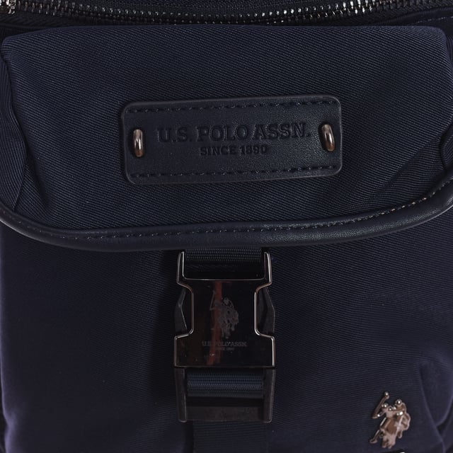 Men's shoulder bag from the U.S. POLO ASSN brand.
 Synthetic material exterior.
 Top zipper closure.
 Front Exterior: One zipper pocket and one buckle closure pocket.
 Rear exterior: One zipper pocket.
 Front interior: One zipper pocket, one open pocket and 4 pen compartments.
 Back interior: Two pockets with velcro closure.
 Adjustable strap.
 Interior lining with brand print.
 Brand logo on the front.
 Measures: 23x20x7cm
 Composition: 80% Nylon, 20% Polyurethane
 Care:
Clean with a wet cloth.