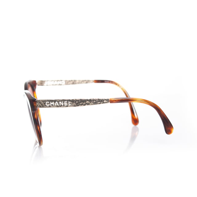 VINTAGE, RRP AS NEW
Chanel, round tortoise sunglasses with metal Chanel cut out temples in gold. The item is in good condition. The lenses have very light scratches and The temples are slightly apart (need adjustment). Comes with case and dust cloth.
 • CONDITION: good

• CODE: 5440

• MEASUREMENTS: height lens 5,5 cm, width lens 6 cm, width frame 14 cm

• MATERIAL: plastic, metal

• COLOR: brown, gold