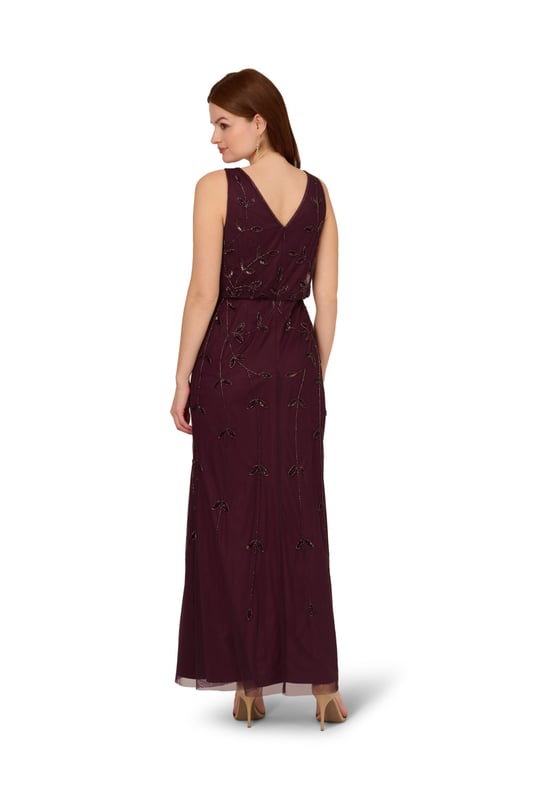 Put a little sparkle on display when you rock this sleeveless blouson gown. This formal dress features a sleeveless blouson bodice, deep v-neckline and back, and a soft skirt. Crafted with a luxe mesh fabric that is fully lined, this evening gown is embellished with sequin and beaded vines. The neckline and armholes of this gown are trimmed in beading for added sparkle. A hidden zipper closure at the centre back completes the design. This sleeveless beaded gown is a stunning look for a wedding guest or bridal party and pairs well with neutral or metallic accessories.