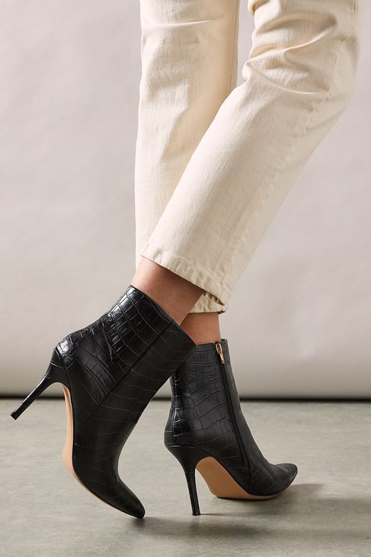 Sleek pointed toe design for a sophisticated silhouette
        Textured faux leather with a chic crocodile-inspired pattern
        Stiletto heel measuring between 7-9cm for an elegant boost
        Ankle-length style with a side zip for easy wear
        Versatile day-to-night boot suitable for various occasions
    
    The Corsica Pointed Stiletto Ankle Boots from Wallis are the epitome of versatile glamour. These striking boots showcase a refined pointed toe and a sleek stiletto heel, perfect for the woman who appreciates sophistication with a modern edge. The textured faux leather exterior adds a touch of luxury, while the crocodile-inspired pattern lends an air of exotic allure. Ideal for transitioning from day to evening, these boots can be styled with tailored trousers and a crisp blouse for a polished office look, or paired with a flowing midi dress for an elegant dinner ensemble. The ankle-length cut offers flexibility in styling, working beautifully with both trousers and skirts. Whether you're heading to an important meeting or a night out with friends, these Wallis boots will ensure you step out in style and confidence.