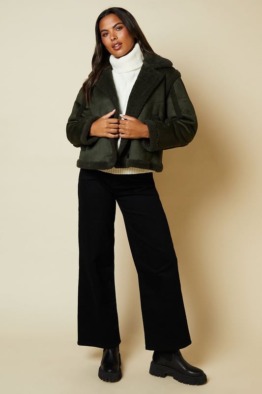 Cropped aviator-style jacket with suede-like finish
        Plush shearling-effect collar and lining for warmth
        Double-breasted front with button fastenings
        Relaxed fit with dropped shoulders for easy layering
        Side pockets for practicality and style
    
    Embrace the cool-weather season with this chic suede cropped aviator jacket from Dorothy Perkins. Perfect for the fashion-forward woman who values both style and comfort, this versatile piece is ideal for casual outings and family gatherings. The jacket's cropped silhouette adds a modern twist to the classic aviator style, while the plush shearling-effect details provide cosy warmth. Style it as seen on the model with a crisp white turtleneck, wide-leg trousers, and chunky boots for a trendy brunch look. Alternatively, throw it over a floral midi dress and ankle boots for a charming baby shower ensemble. The relaxed fit allows for easy layering, making it a go-to choice for unpredictable British weather. Whether you're meeting friends for coffee or running weekend errands, this jacket will keep you looking effortlessly stylish and feeling comfortable all day long.
