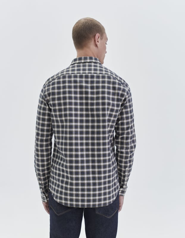 This navy shirt has collared neck and long sleeves. The shape is slim and short, with checked pattern.