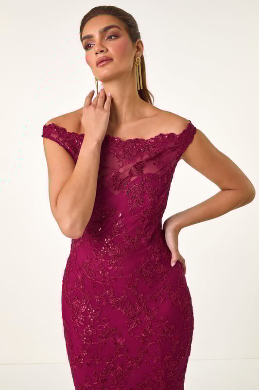 Lace Scallop Edge Front Split Maxi Dress from Roman. Get ready to make a statement in our stunning lace maxi dress. The feminine bardot neckline is adorned with delicate scalloped lace details, adding a touch of elegance to the look. Crafted from a stretch woven fabric, this bodycon dress hugs your shape beautifully and finishes at a flattering maxi length with a mermaid edge and front split for added drama. Pair with heels and a bolero for an unforgettable look!