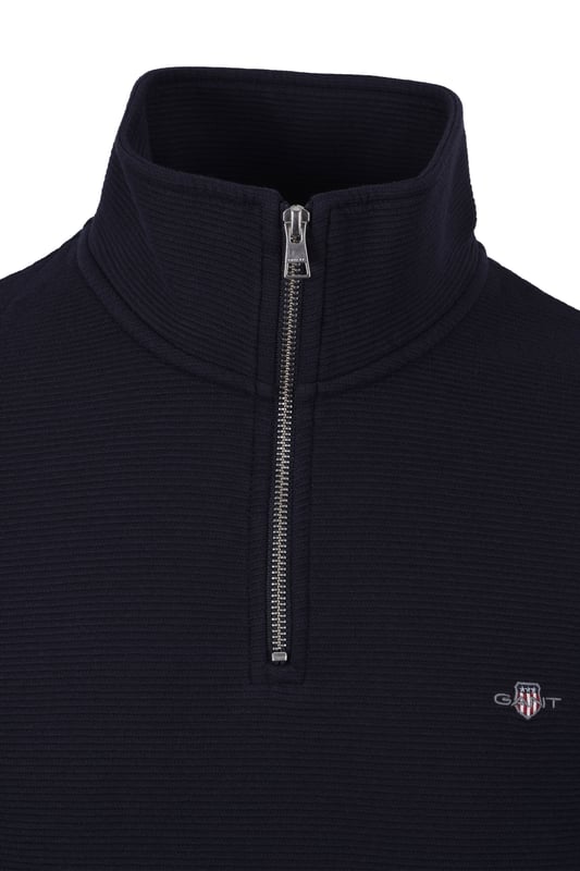 Gant Texture Half Zip Knitwear in Evening Blue
Experience timeless style with the Gant Texture Half Zip Knitwear. Crafted from a luxurious blend of lightweight cotton, this sweater offers exceptional comfort and a touch of sophistication. The all-over micro-textured design adds a subtle dimension, while the classic half-zip collar provides a versatile and stylish look.   
 
Key Features:

Classic half-zip collar for easy layering and adjustment   
Ribbed cuffs and hem for a secure and polished look   
Embroidered GANT archive shield graphic at the chest for a touch of heritage   
Lightweight and comfortable cotton blend for all-day wear   
Wash with similar colours
Material: 100% Cotton