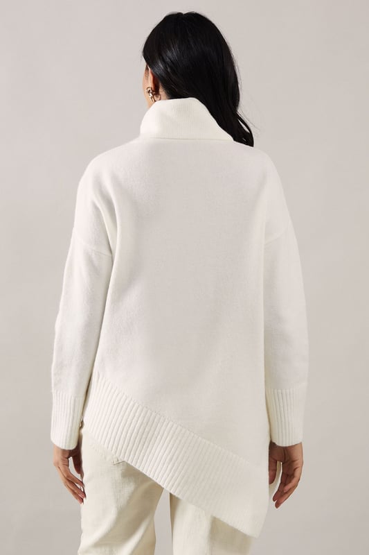 Asymmetric hemline for a modern, eye-catching silhouette
        Cosy roll neck design perfect for chilly days
        Relaxed fit through the body for effortless comfort
        Long sleeves with ribbed cuffs for a snug fit
        Versatile knit suitable for various casual occasions
    
    Embrace sophistication and comfort with this Wallis Petite Plain Asymmetric Roll Neck Jumper. The unique asymmetric hemline adds a contemporary twist to this classic knitwear piece, making it a standout addition to your wardrobe. Perfect for those who appreciate both style and cosiness, this jumper is ideal for family gatherings, casual outings, or relaxed evenings with friends. Style it with dark wash jeans and ankle boots for a chic daytime look, or pair it with tailored trousers and ballet flats for a more polished ensemble. The versatile design allows for easy transition from day to night, ensuring you always look put-together without compromising on comfort. Add delicate gold jewellery to enhance the jumper's elegant appeal, making it a go-to piece for those moments when you want to feel both glamorous and at ease.